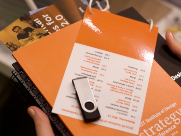 Conference swag with USB drive, booklet, and notebook related to design