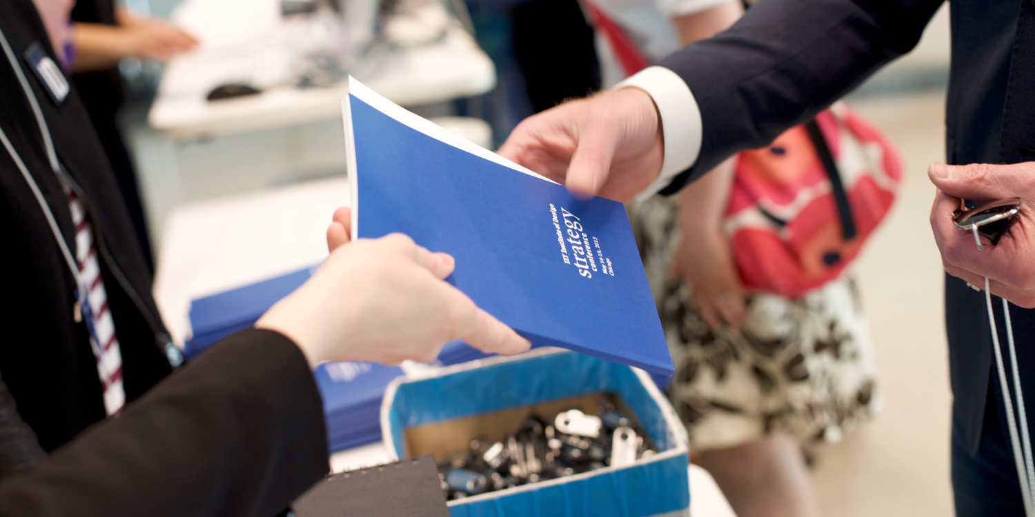 2 human hands exchanging a strategy booklet deliverable related to user experience research