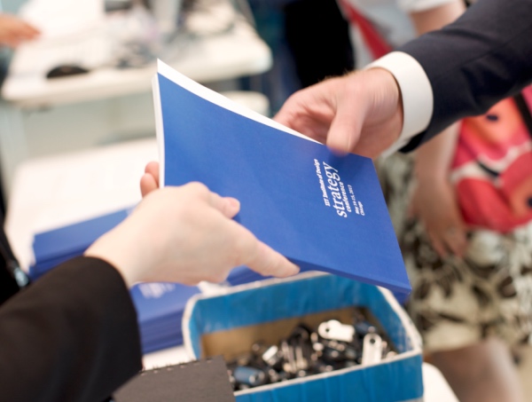 2 human hands exchanging a strategy booklet deliverable related to user experience research