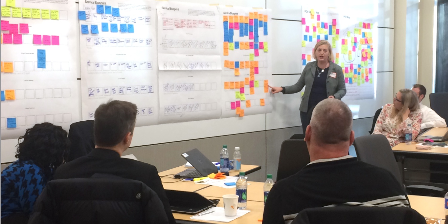 Woman presenting service blueprint to corporate teammates