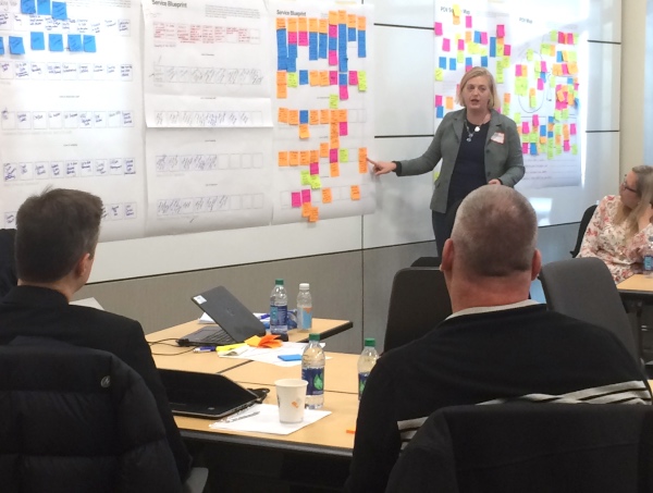 Woman presenting service blueprint to corporate teammates