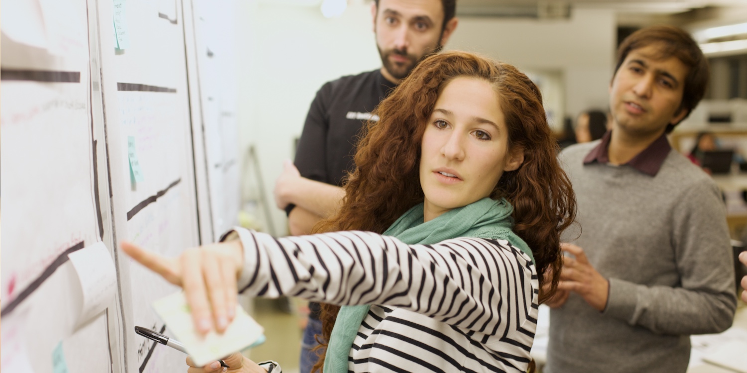 User Experience consultants pointing to and discussing product insights at the wall